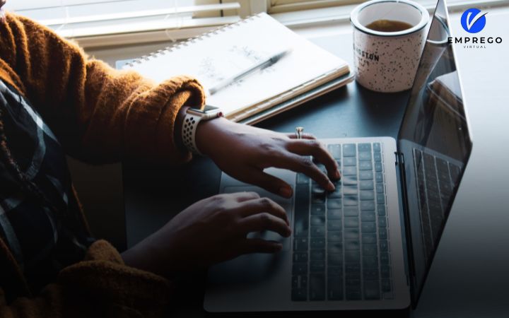 Pessoa digitando em um laptop com ícones de redes sociais ao redor com a logo da emprego virtual